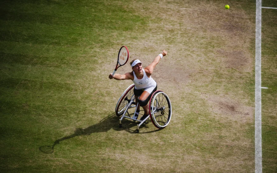Wheelchair tennis player serving on a grass court, seen from above