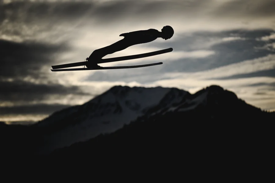 Ski jumper silhouetted against the mountains at dusk