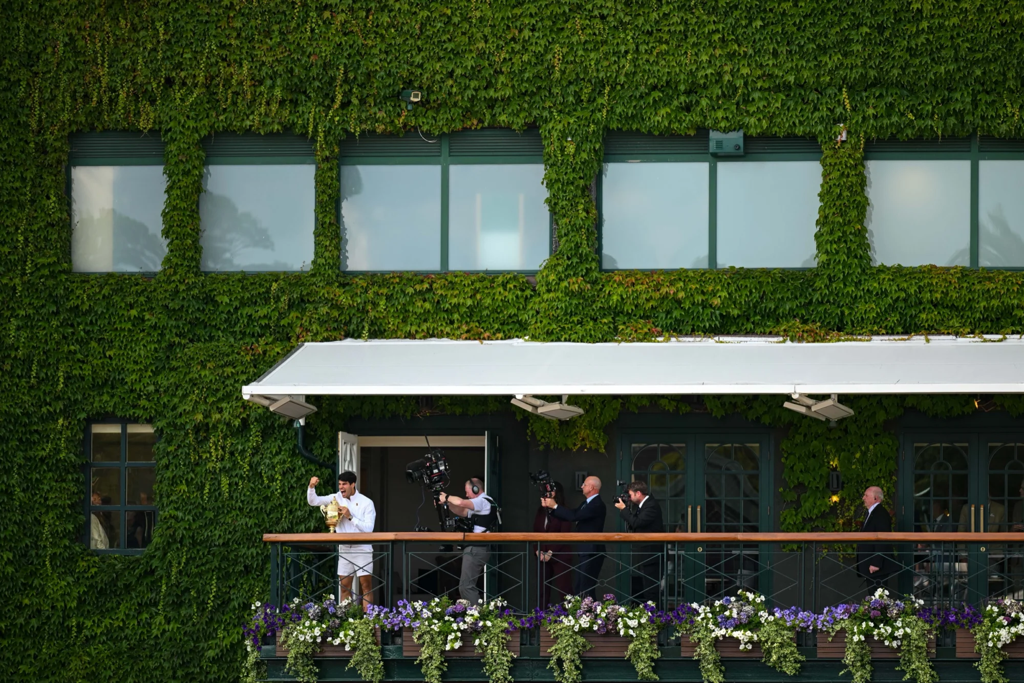 Champion presenting the trophy on the ivy-covered Centre Court balcony at Wimbledon