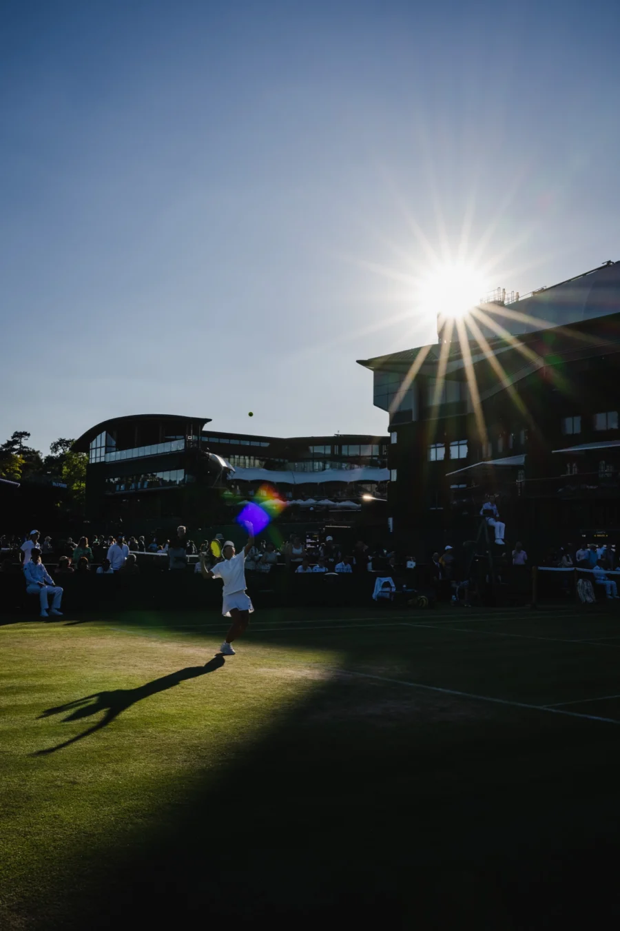 Sunburst over a grass tennis court and stadium