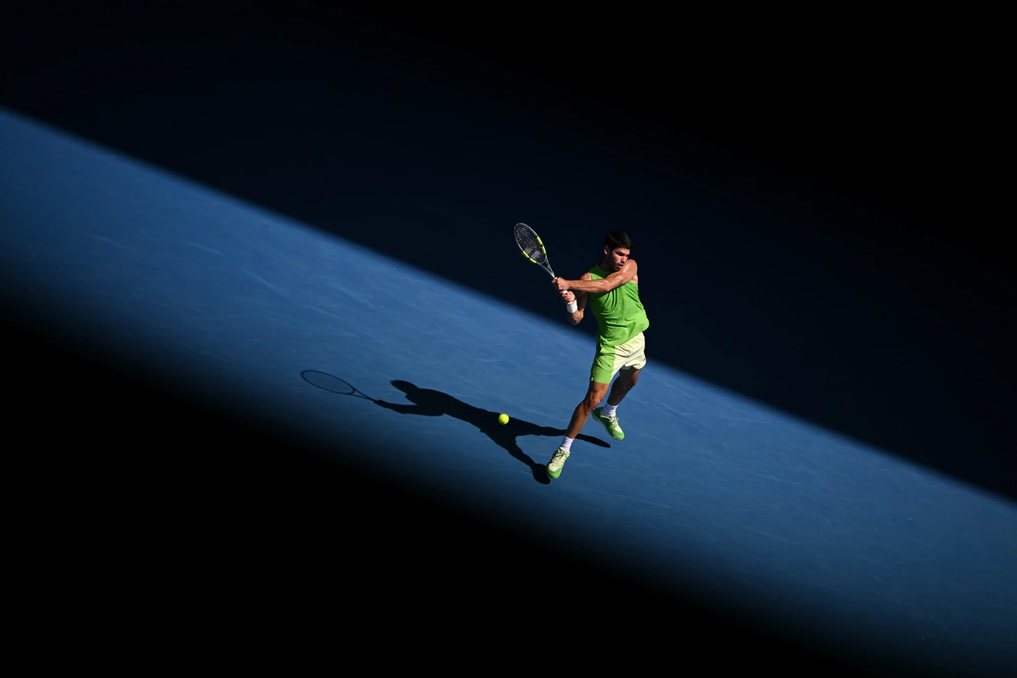 Tennis player in a beam of light on a blue hard court, Australian Open 2026