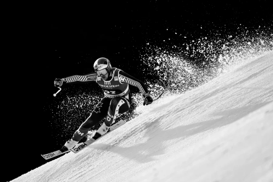 Alpine ski racer carving through powder snow, black and white, World Cup Kvitfjell 2026