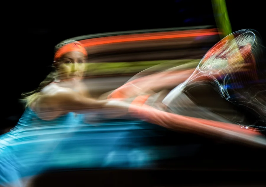 Tennis player hitting the ball, colourful long-exposure motion blur